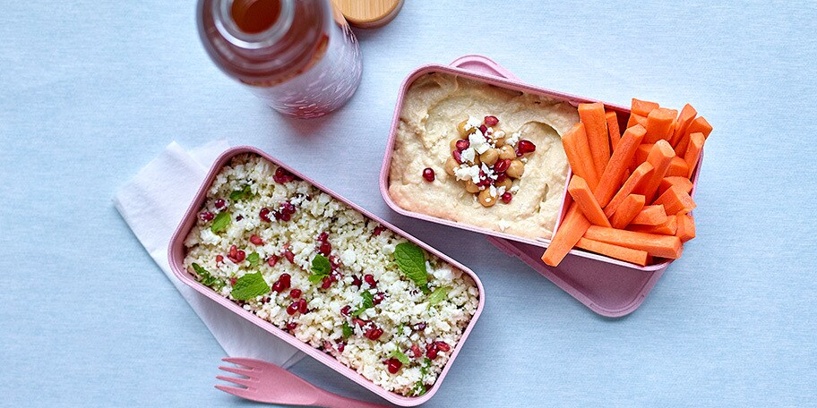 Lunchbox met bloemkooltabouleh en -hummus, wortelstaafjes en ijsthee met citrusvruchten