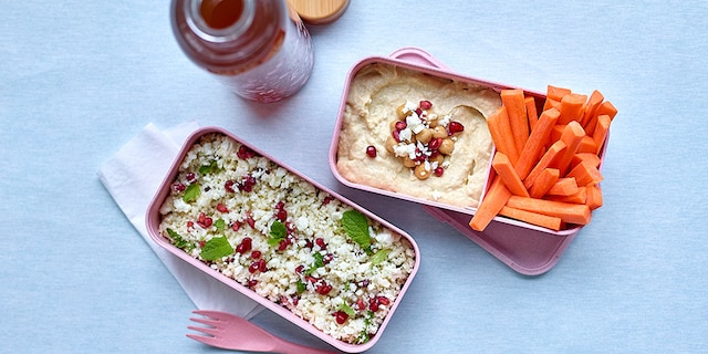 Lunchbox met bloemkooltabouleh en -hummus, wortelstaafjes en ijsthee met citrusvruchten