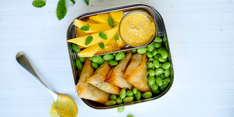 Lunchbox met samosa’s, mango en edamameboontjes