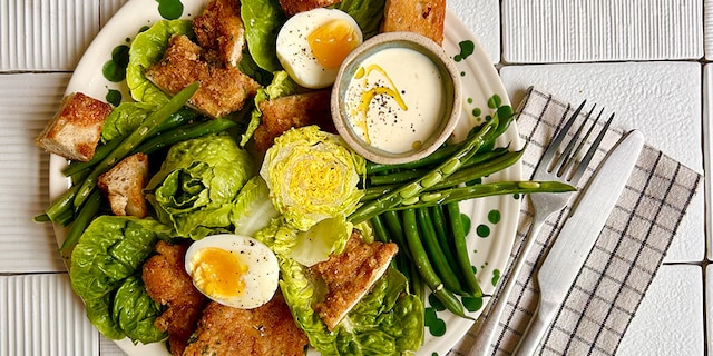 Salade César au veau pané, croûtons, œufs mollets et légumes verts