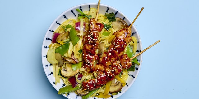 Brochettes de poulet laquées et nouilles sautées aux légumes 