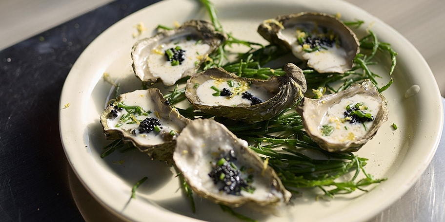 Gerookte oesters op de barbecue met sjalot-dragon saus