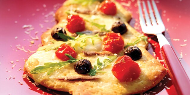 Pizza in de vorm van een kerstboom met zwarte olijven kerstomaten en mozzarellaparels